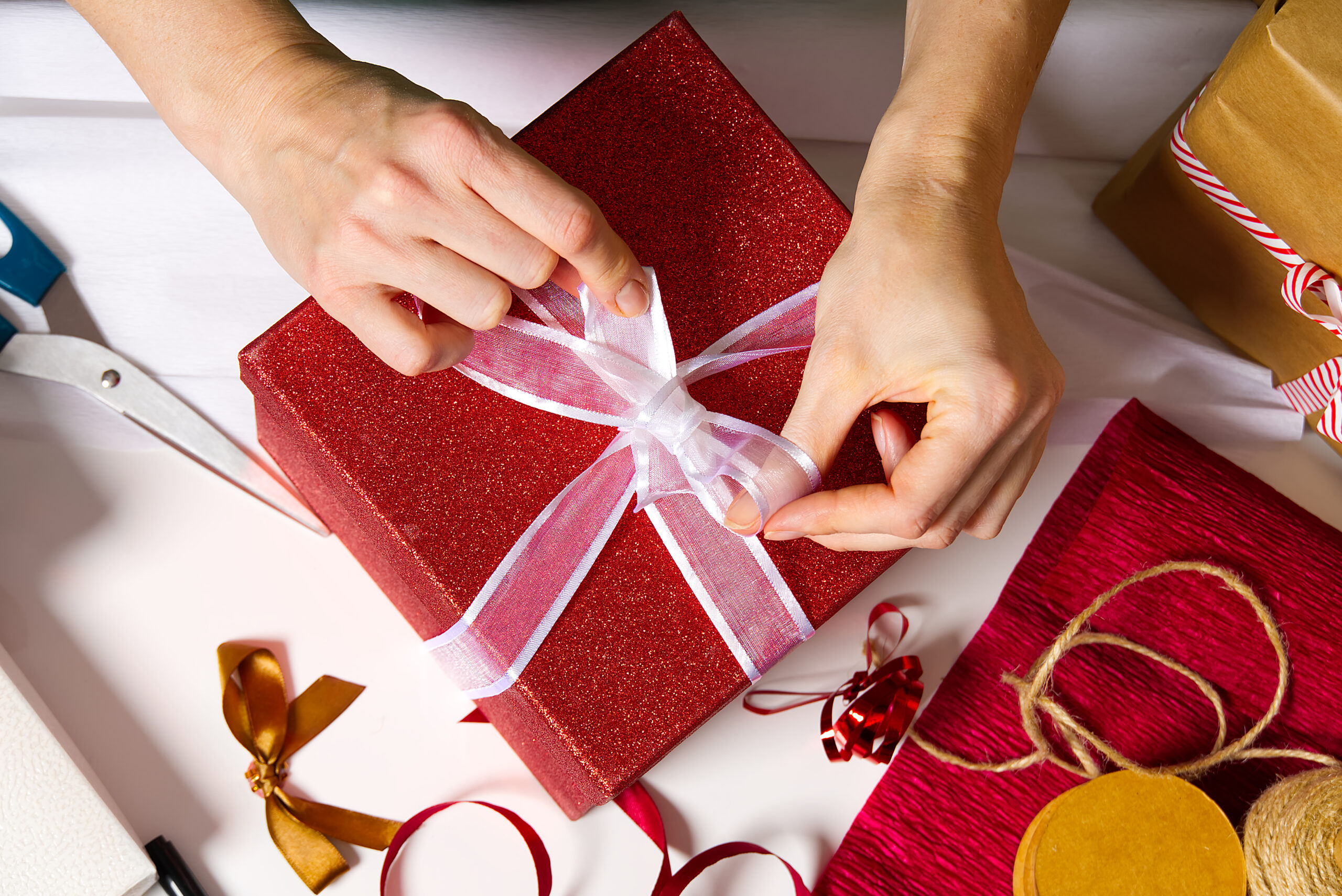 A person tying a red gift box for christmas