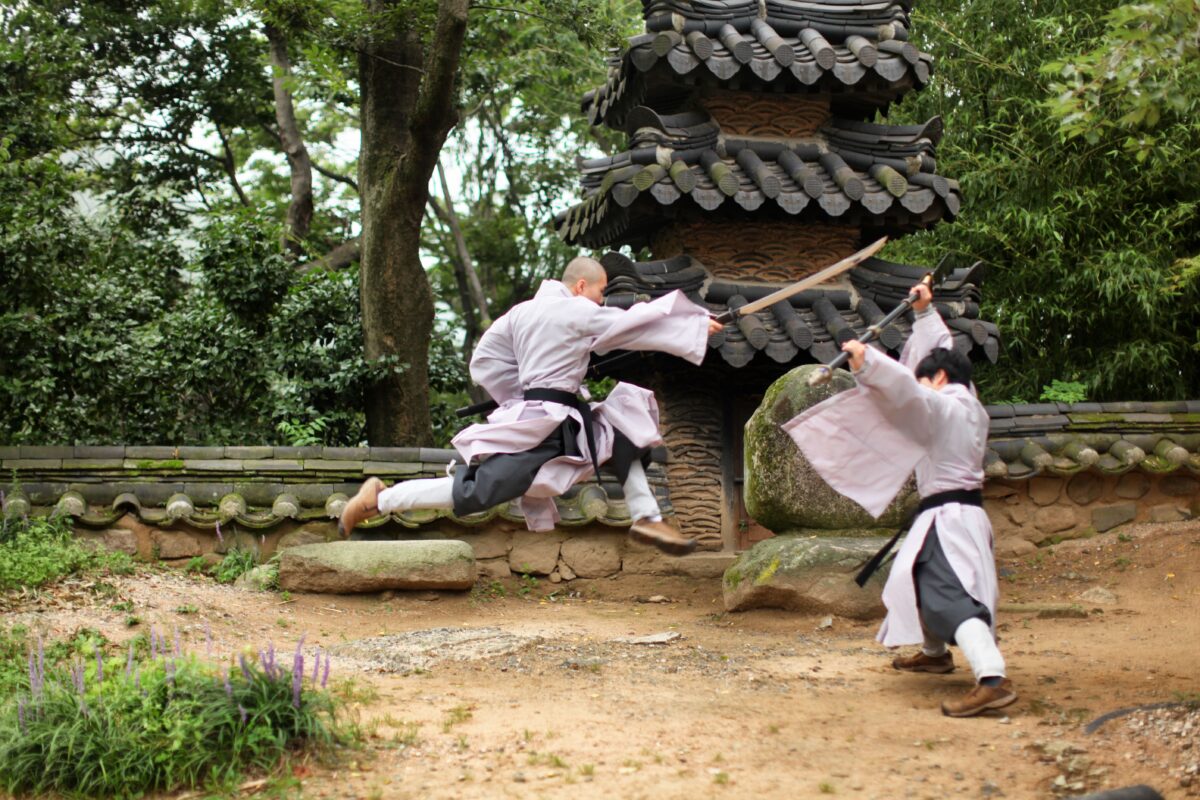 Two martial artists fighting each other with weapons