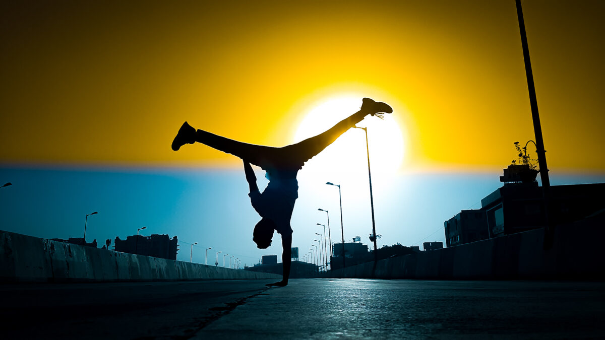 A freestyle dancer doing a nike airfreeze in front of the sun going down